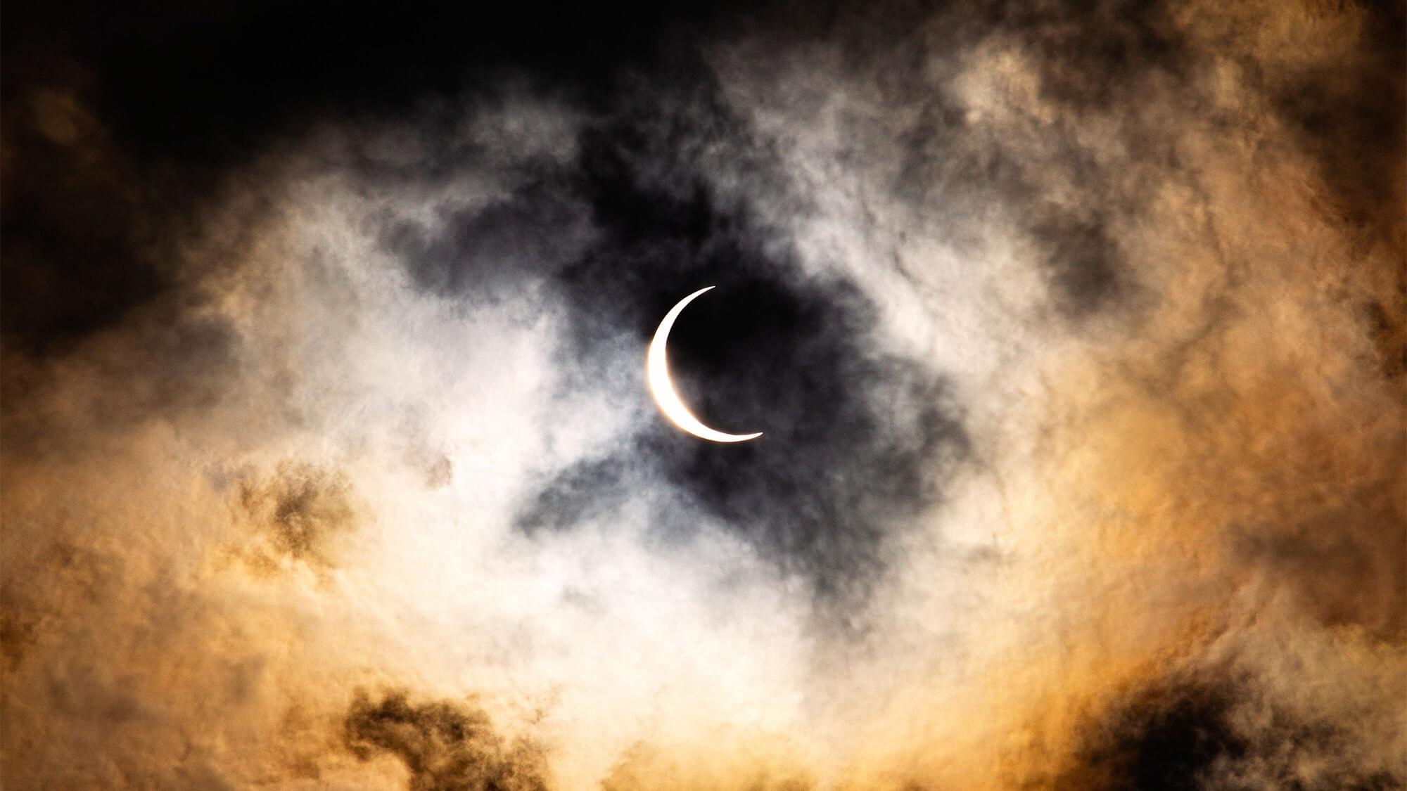 Hazy clouds partially covering a crescent moon