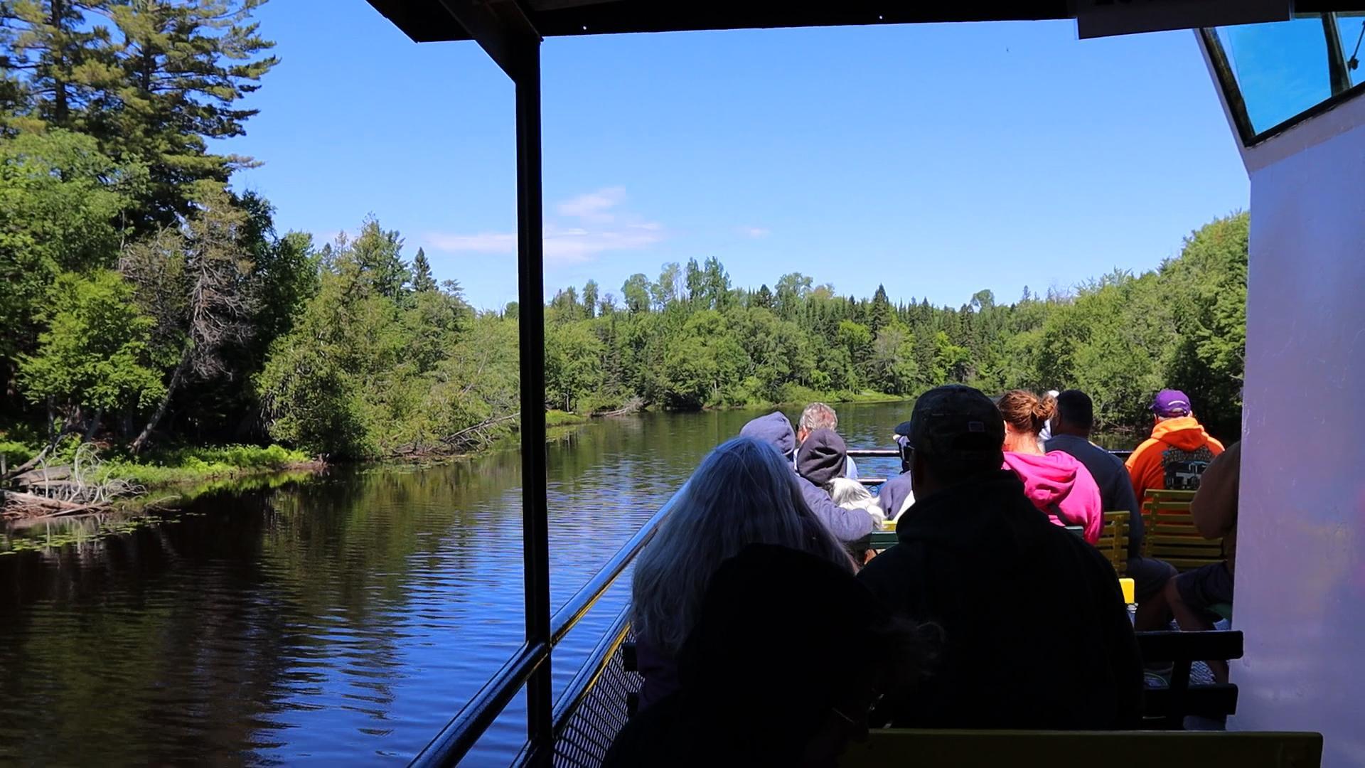 Passengers aboard the Riverboat Tour looking out at trees.