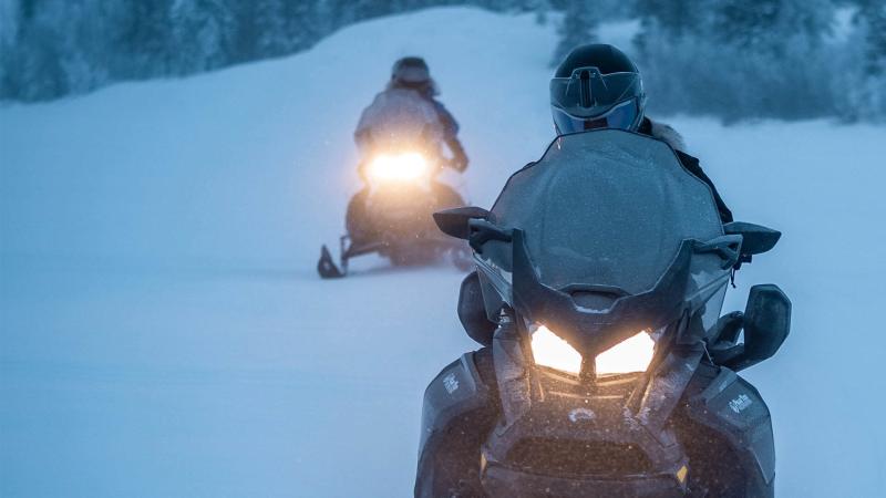 Two snowmobiles riding on a trail in Tahquamenon Country