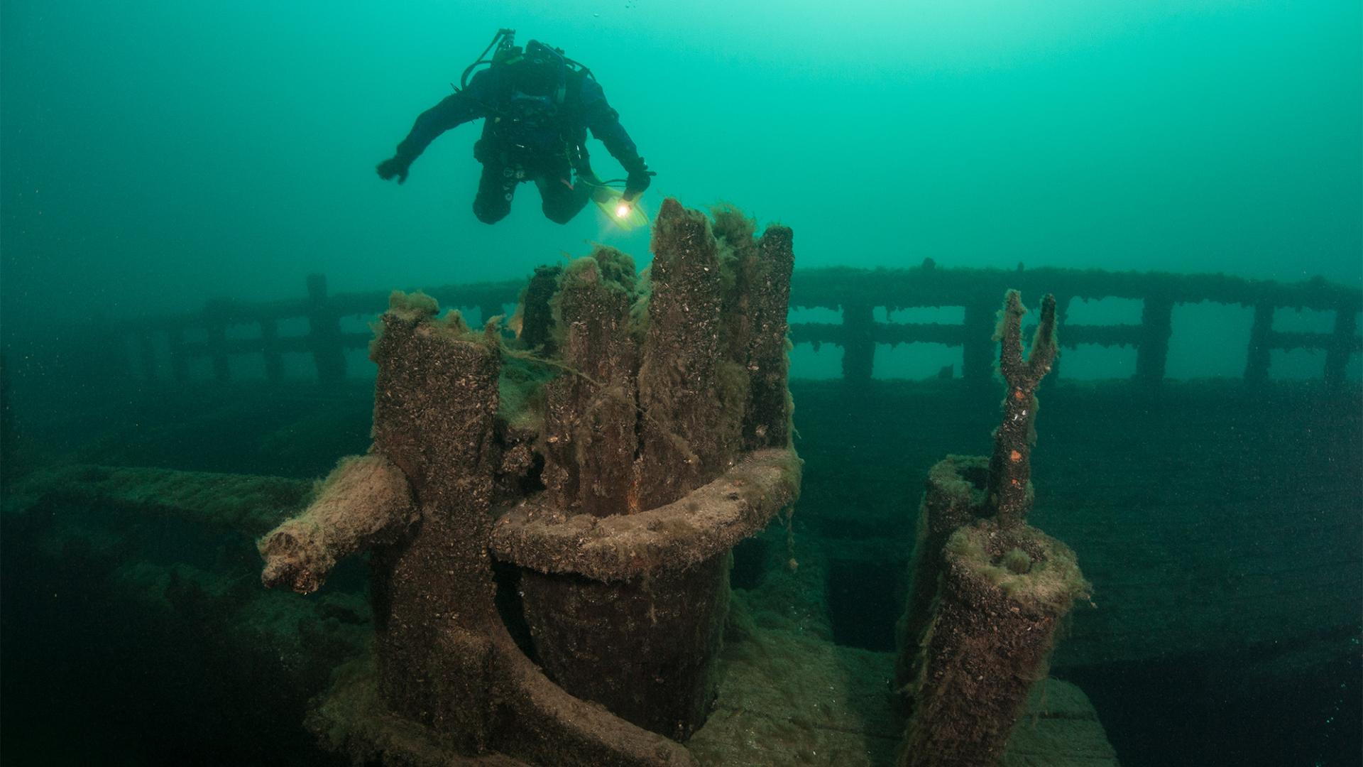 Scuba Diver swimming above a wrecked ship underwater.