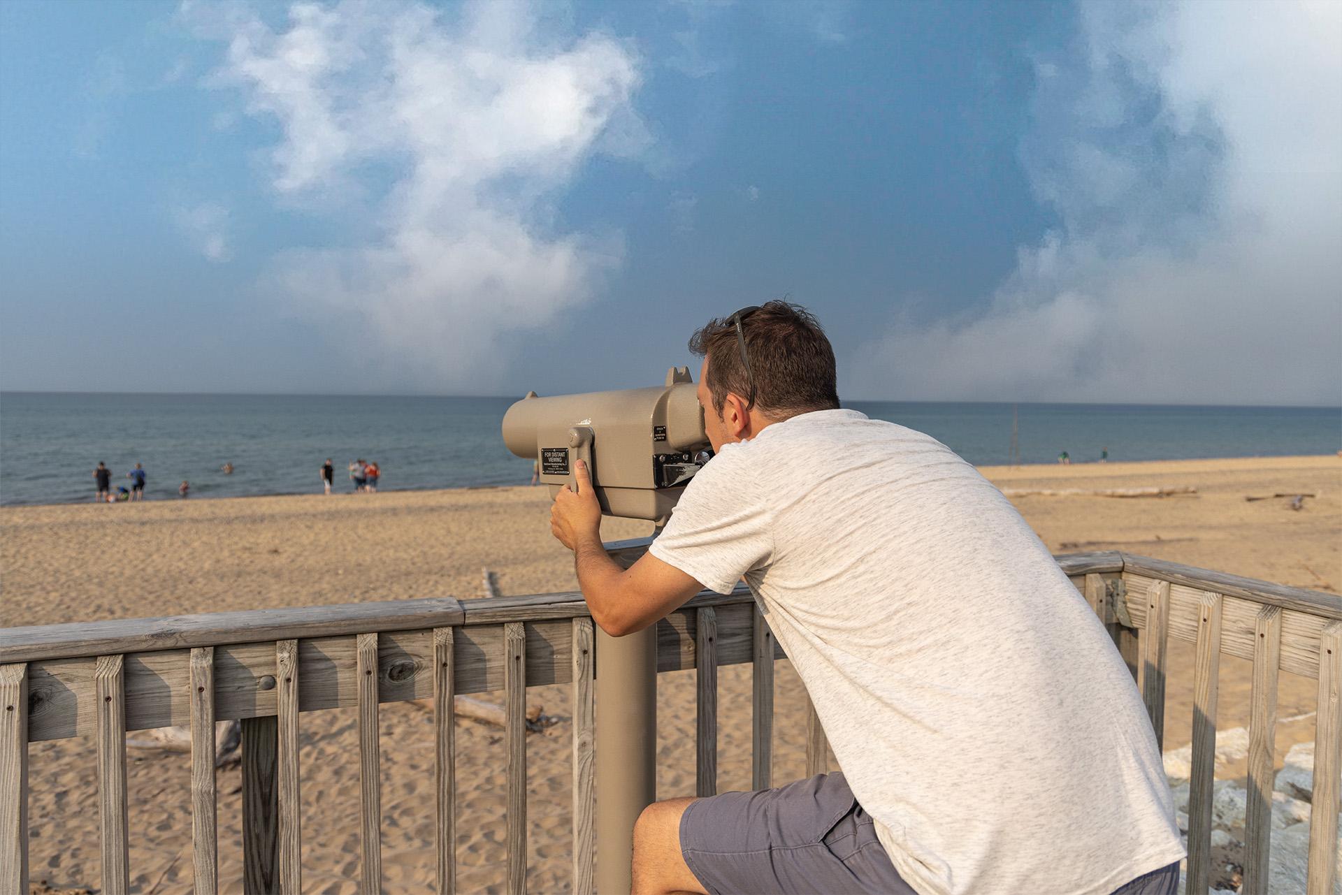 A person looking through binoculars at the Whitefish Point Bird Observatory