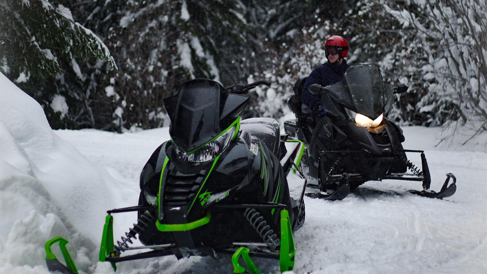 Two snowmobiles on a snowy trail