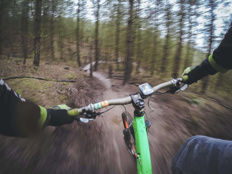 POV biker racing down a dirt track in the forest