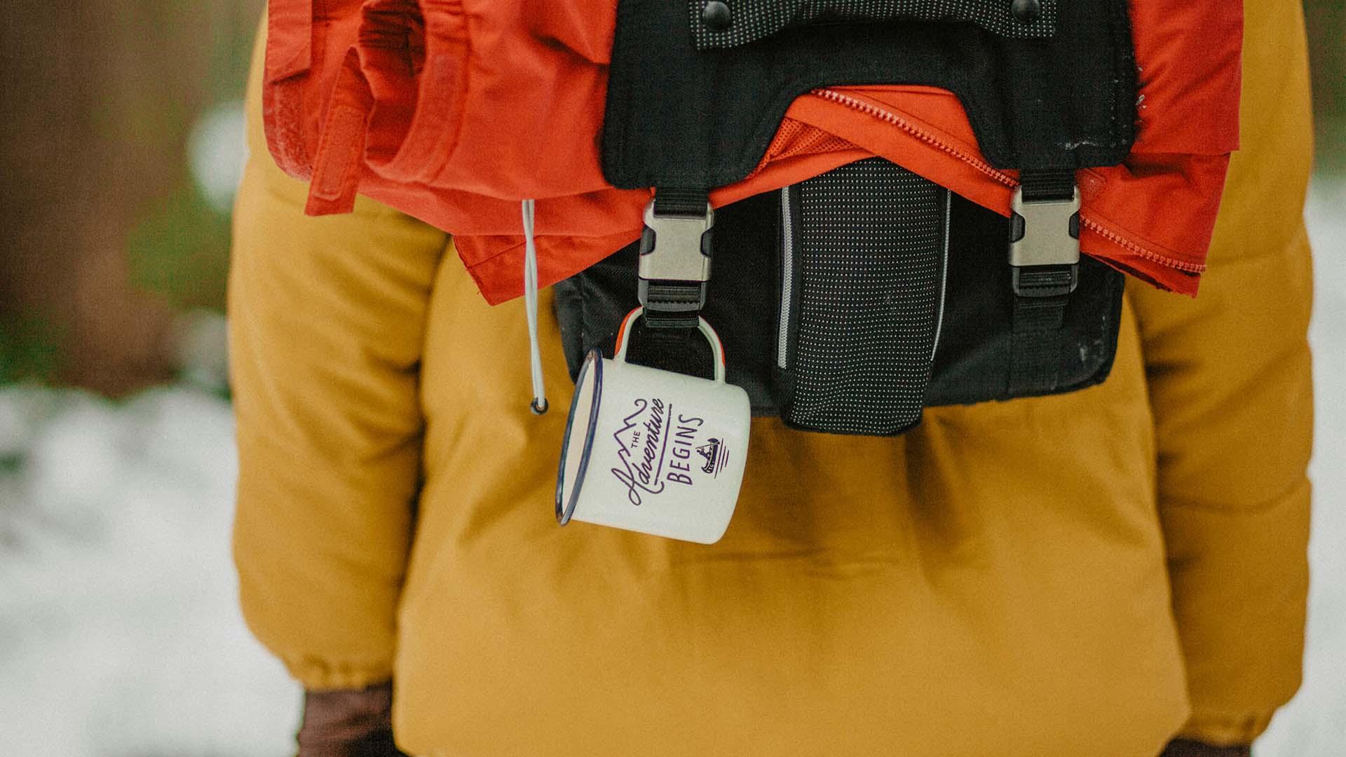  A hiker with backpack and coffee cup.