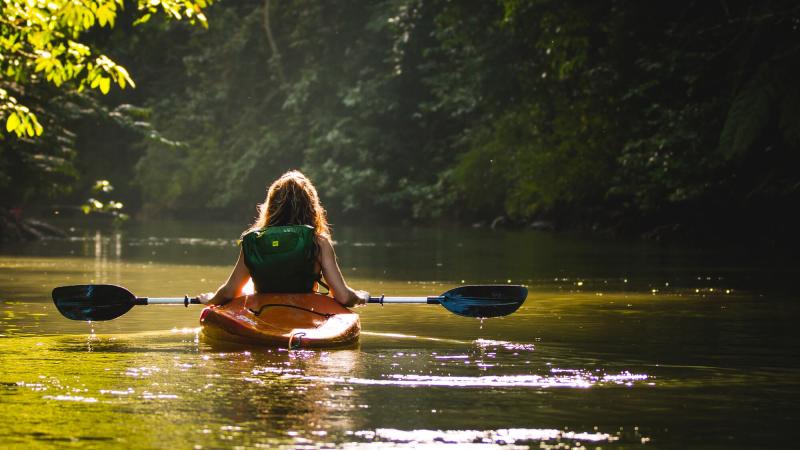 a woman kayaking gently down a river