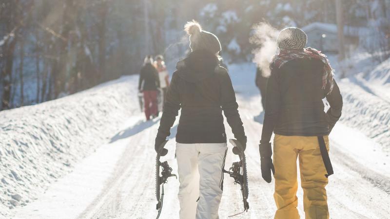 2 people in snow gear walking down a snow-lined road